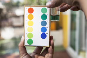 hand holding water ph testing test comparing color to indicated